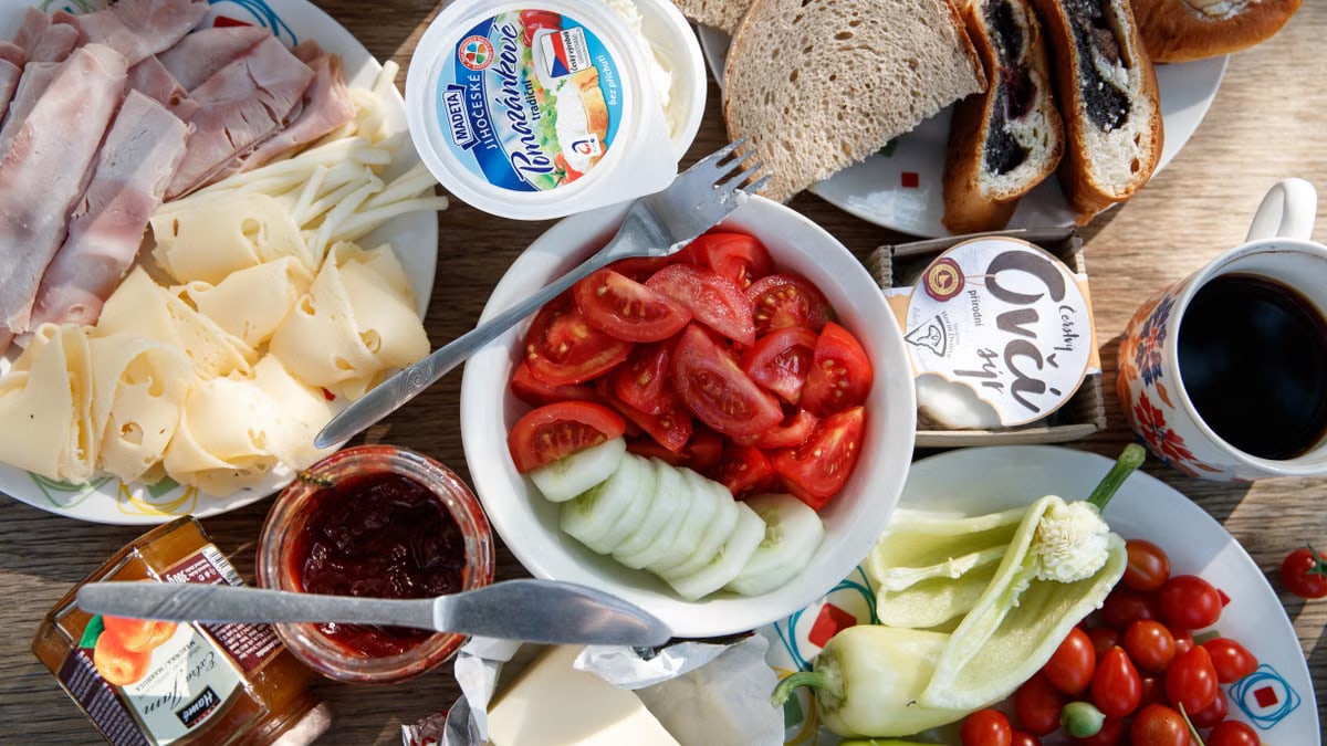 Delicious breakfast setup with cheese, cold cuts, bread, and fresh vegetables.